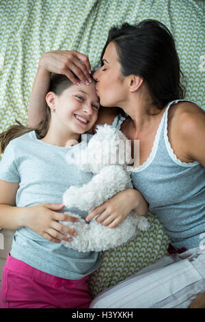 Mutter Tochter Stirn auf Bett küssen Stockfoto