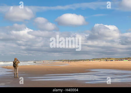 Reife Frau aufnehmen eines Fotos mit einer Kompaktkamera am Strand von Scheveningen, Zuid-Holland, Niederlande. Stockfoto