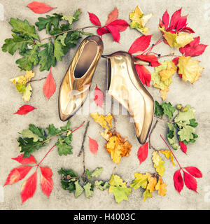 Herbstlaub und goldenen Schuhen. Mode flach zu legen. Vintage-Stil getönten Hintergrund Stockfoto
