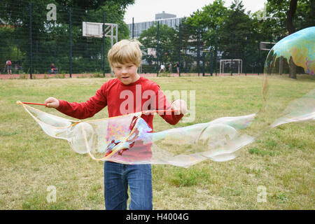 Junge spielt mit Seifenblasen im park Stockfoto