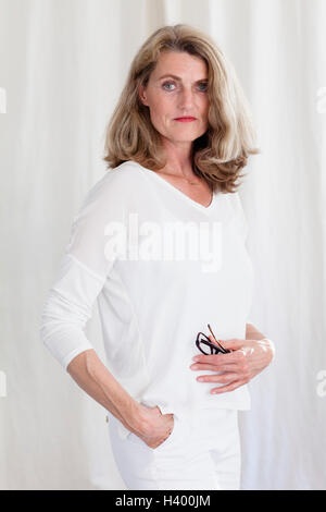 Porträt von zuversichtlich Reife Frau stehend gegen weißen Vorhang Stockfoto