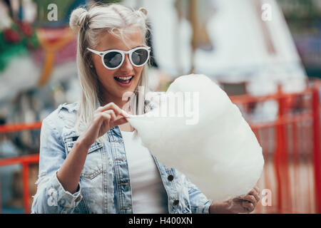 Modisch junge Frau mit Sonnenbrille beim Essen Zuckerwatte im freien Stockfoto