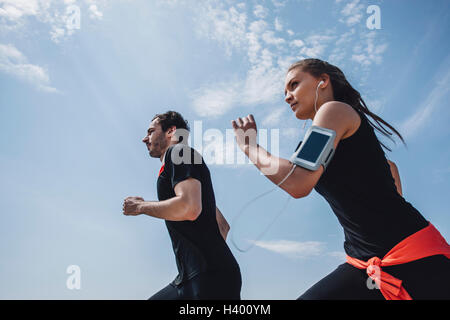 Niedrigen Winkel Ansicht der junge Mann und Frau Joggen gegen Himmel Stockfoto