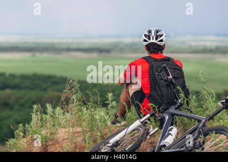 Rückansicht der Mann sitzt mit dem Mountainbike auf Hügel Stockfoto