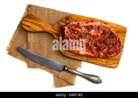 RAW marinierte Schweinesteak, Paprikaflocken, Vintage Messer isoliert auf weißem Hintergrund. Ansicht von oben. Stockfoto