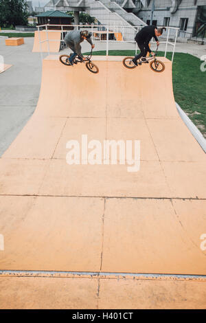 Erhöhte Ansicht von Freunden Radfahren auf Rampe am Skateboard-park Stockfoto