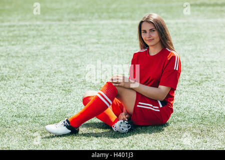 Porträt von fröhlichen Teenager Fußballspieler sitzen auf Feld Stockfoto