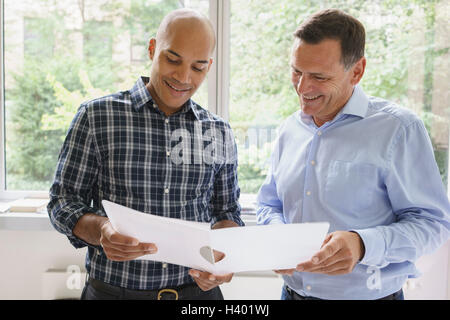 Lächelnde Geschäftsleute diskutieren über Datei gegen Fenster Kreativbüro Stockfoto