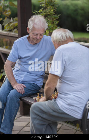 Senioren Freunde spielt Schach auf Parkbank Stockfoto