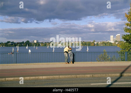 Deutschland, Hamburg, Blick auf die Stadt, Außenalster See, Brücke, paar, umarmen, Ansicht, Rückansicht, Europa, Stadt, Hansestadt, Gewässer, Segelboote, Segeln, Freizeit, Naherholungsgebiet, Partnerschaft, verliebt sich in stehen, genießen, erholen, Freizeit, Summe Stockfoto