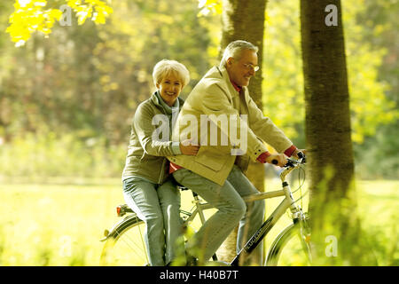 Waldweg, Senior, Fahrrad fahren, Gepäckträger, Frau, sitzen, Senioren, älteres Paar, Fröhlichkeit, Spaß, Lächeln, Freizeitmode, Freizeit, Fitness, fit, agil, Initiative, zusammen, Sport, sportlich, Bewegung, Aktivität, Zyklus Eingabeaufforderung, Holz, Weg, autu Stockfoto