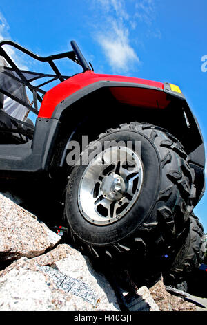 roten Vierrad-Motorrad stehend auf einem Haufen aus Granit auf dem Hintergrund des blauen Himmels Stockfoto