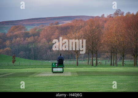 Mann fahren eine Fahrt auf der Walze, bereitet das Wicket eines Dorfes cricket Pitch - Bolton Abbey Cricket Club, Yorkshire Dales. Stockfoto