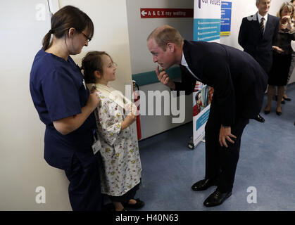 Der Duke of Cambridge deutet auf seine Zähne, als er sieben Jahre alte Patient Anna Kape,, die einen fehlenden Schneidezahn und gebrochenen Arm, während seines Besuchs in der trifft "Treten Sie ein in Gesundheit" militärischen Beschäftigung Programm hat in Basingstoke und North Hampshire Hospital. Stockfoto