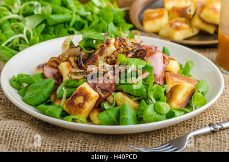 Kartoffel-Gnocchi mit Sommer-Salat, Speck und Röstzwiebeln. Gnocchi gekocht und dann auf Pfanne für Golden knusprig gebraten Stockfoto