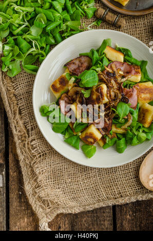 Kartoffel-Gnocchi mit Sommer-Salat, Speck und Röstzwiebeln. Gnocchi gekocht und dann auf Pfanne für Golden knusprig gebraten Stockfoto