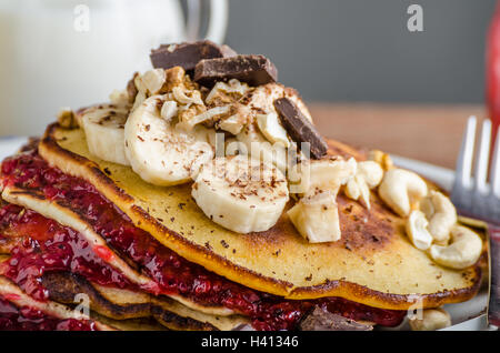 Hausgemachte Pfannkuchen mit Marmelade Johannisbeere, Bananen und Schokolade, gerösteten Erdnüsse an der Spitze Stockfoto