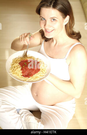 Frau, schwanger, Beinen, Spaghetti, Essen, glücklich, anzeigen Kamera, Schwangerschaft, Schwangerschaft, 25 Lächeln - 35 Jahren, schwanger, Schwangerschaft, Baby-Bauch, Mittagessen, Nudelgericht, Nudeln, Körper Gericht, Lieblingsgericht, Ernährung, Hunger, Sitomania, verlangen, Begierde, Essen Stockfoto