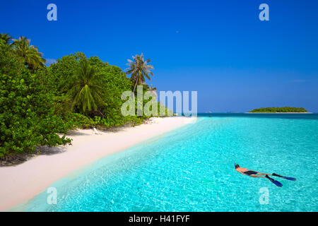 Junger Mann Schnorcheln in tropischen Insel mit Sandstrand, Palmen und Türkis klarem Wasser Stockfoto
