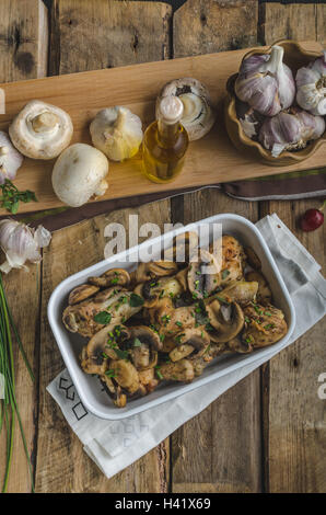 Gebratenes Huhn Trommelstöcke mit Knoblauch und Pilzen, garniert mit frischen Kräutern aus Bio-Garten Stockfoto