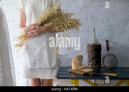 Kaukasische Frau mit Bouquet von Weizen in der Nähe von Schnittbrot Stockfoto