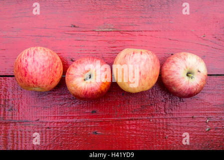 Nahaufnahme der Reihe von roten Äpfeln auf roten Holztisch Stockfoto