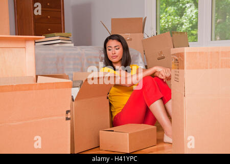 Hispanische Frau sitzen auf Boden mit Umzugskartons Stockfoto