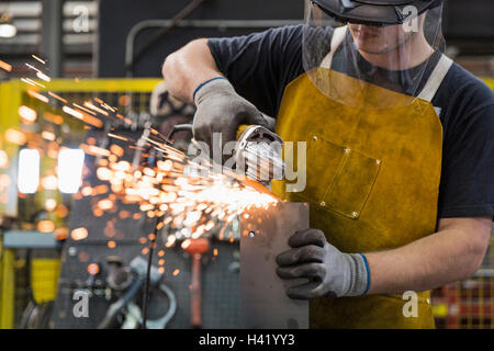 Kaukasische Arbeiter Schleifen Metall im Werk Stockfoto