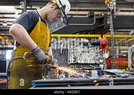 Kaukasische Arbeiter Schleifen Metall im Werk Stockfoto