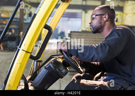 Schwarze Arbeiter fahren Gabelstapler in Fabrik Stockfoto