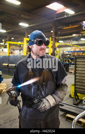 Kaukasische Schweißer mit Lötlampe in Fabrik Stockfoto