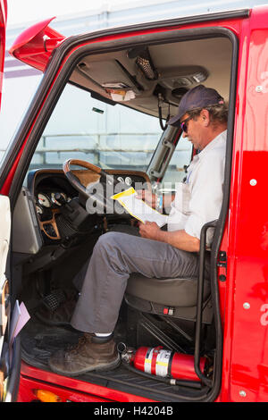 Kaukasische semi-LKW-Fahrer lesen Papierkram Stockfoto