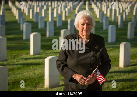 Kaukasische Witwe mit amerikanischen Flagge im Friedhof Stockfoto