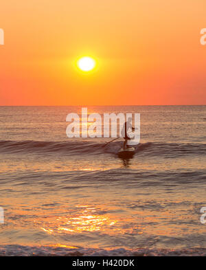 Silhouette des Mannes Paddling auf Wellen des Ozeans Stockfoto