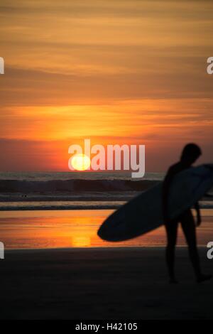 Silhouette der ein Surfer mit einem Surfbrett bei Sonnenuntergang, Costa Rica Stockfoto
