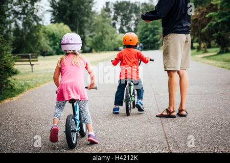 Vater beobachtete Tochter und Sohn Fahrrad fahren Stockfoto