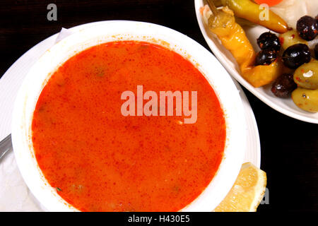 Hühnersuppe serviert mit gemischten Oliven und Zitrone Stockfoto