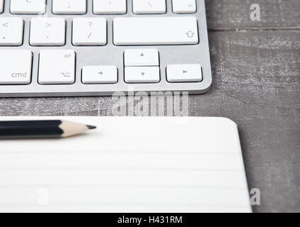 Tastatur mit Bleistift auf offenen Arbeitsmappenblatt auf Schreibtisch Stockfoto
