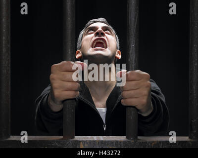 Mann, Gefängnis, Bars, Verzweiflung, schreien, Gitter, Zelle, Gefängnis, Gefängniszelle, eingesperrt, Verbrechen, Strafe, Kriminalität, Verbrecher, Schulden, schuldig, erwischt, Angst, hoffnungslos, entmutigt, psyche, gefangen, Verhaftung, hoffe, hoffe, betteln, Angst vor der Zukunft, Hoffnungslosigkeit, Icon, Konzeption, Problem, Krise, Hilfe, dunkel, düster, schwarz, hoffnungslos, Hilfe suchen, Schrei, Schrei nach Hilfe, Studio, Porträt, Stockfoto