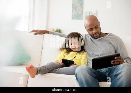 Vater und Tochter, die mit digitalen Tabletten auf sofa Stockfoto