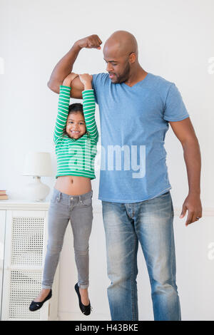 Vater Hebe Tochter mit Bizeps Stockfoto