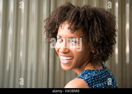 Lächelnde schwarze Frau auf der Suche über die Schulter Stockfoto