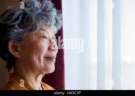 Japanische Frau am Fenster stand lächelnd Stockfoto