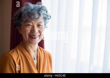 Japanische Frau am Fenster stand lächelnd Stockfoto