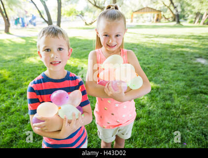 Kaukasische Bruder und Schwester halten Wasserballons Stockfoto