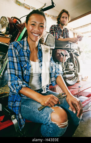 Lächelnder Mann und Frau Motorrad in Garage reparieren Stockfoto