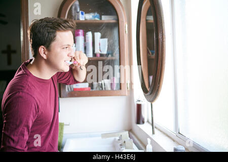 Hispanic Mann Zähneputzen im Spiegel Stockfoto