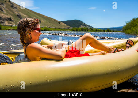 Kaukasische Frau Verlegung im Schlauchboot SMS auf Handy Stockfoto