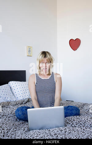 Überrascht kaukasischen Frau mit Laptop am Bett Stockfoto