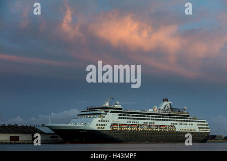 Ein Kreuzfahrtschiff ist während des Sonnenuntergangs am Honolulu Hafen verankert. Stockfoto